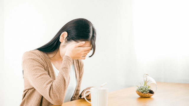 職で顔を押さえる女性の写真