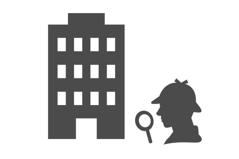企業の建物を前に調査員が実態を確認する様子を象徴したアイコンで、取引先調査・企業実態調査・代表者調査・取引先信用調査など、尾行・張込み・聞き込みによって企業や代表者の実態を確認する企業調査サービスを表現した画像